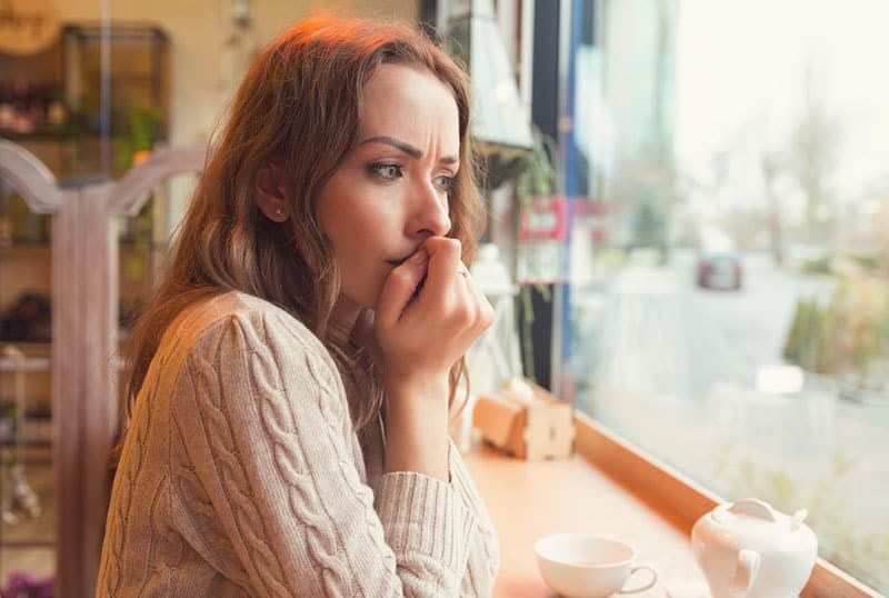 dona ansiosa asseguda al cafè
