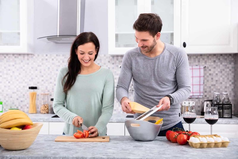 một người đàn ông mỉm cười giúp một người phụ nữ trong nhà bếp