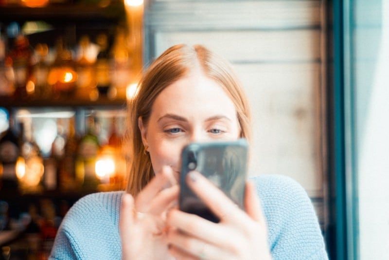 blondinka s črnim pametnim telefonom