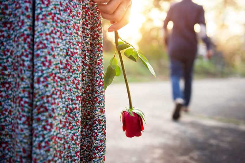 dona trista sostenint una rosa mentre l