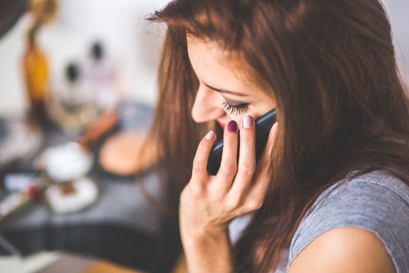 ženska v sivi majici govori po telefonu