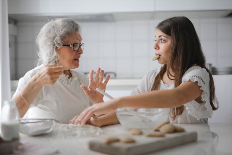 babcia rozmawia z wnuczką siedząc przy stole