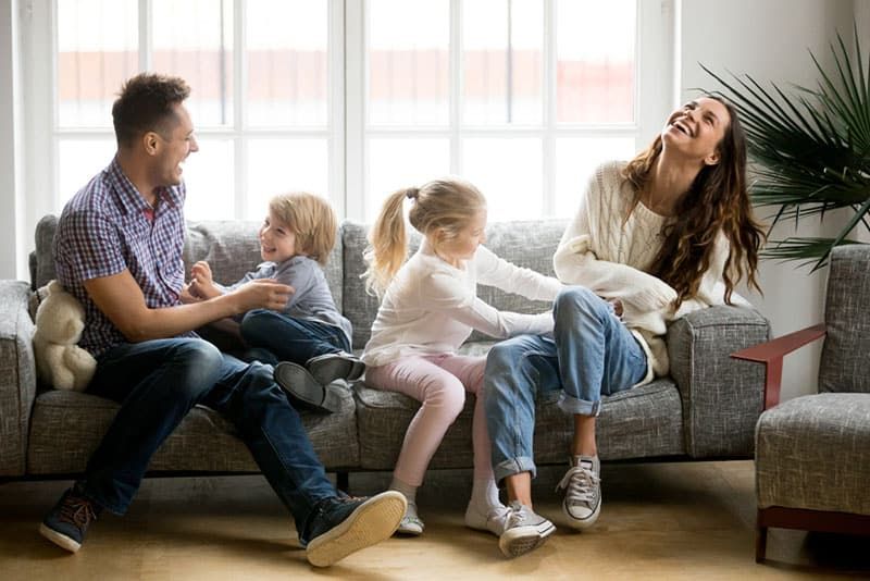 la família fent pessigolles al sofà