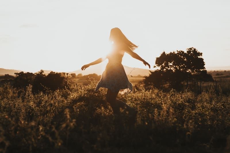 Frau tanzt bei Sonnenaufgang auf dem Feld herum