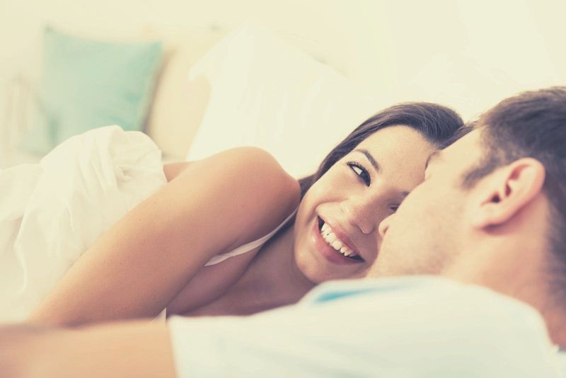 doce casal na cama olhando um ao outro sorrindo enquanto estava deitado