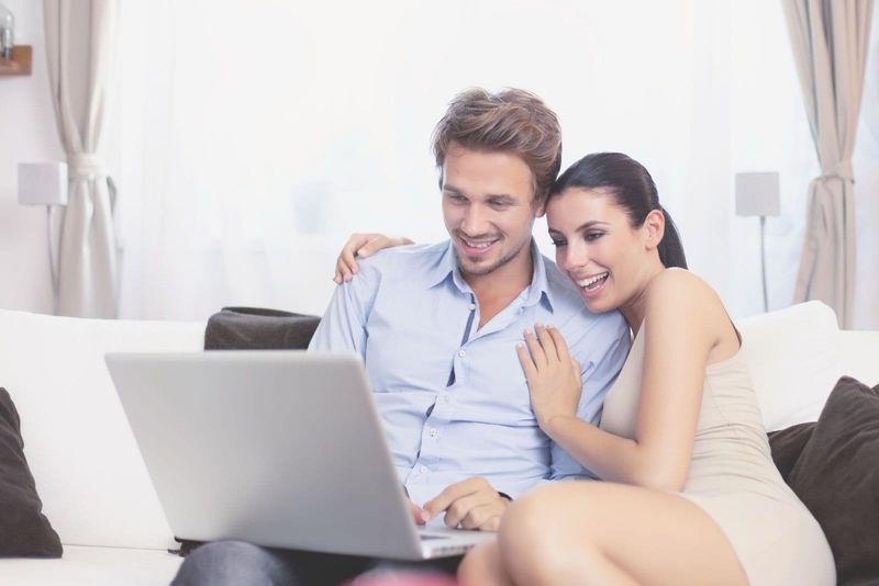 jovem casal na sala olhando para o laptop