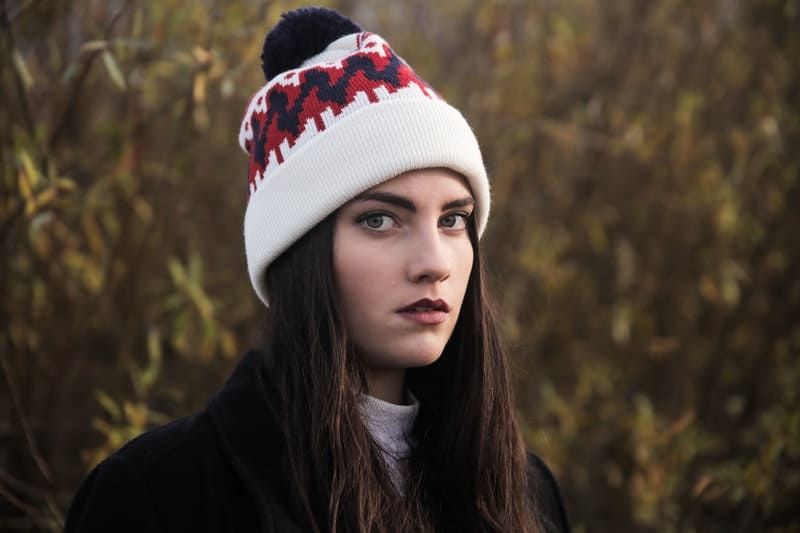 mulher de gorro olhando para a câmera no meio do campo