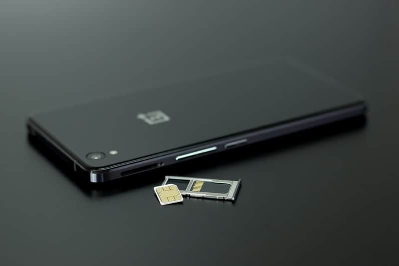 oneplus smartphone preto e branco colocado na mesa preta com cartões sim fora do telefone