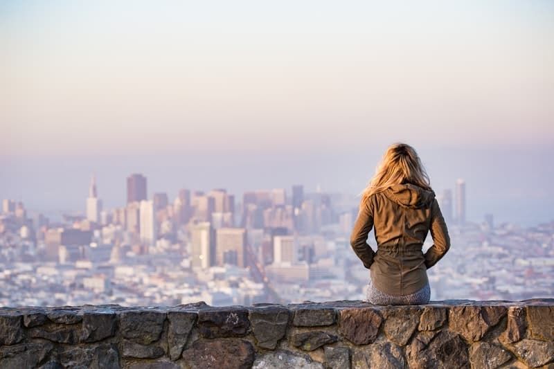 mulher na plataforma de pedra com vista para toda a cidade