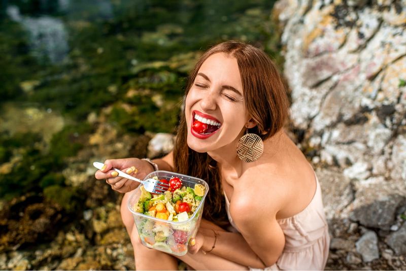 Femeie care mănâncă salată sănătoasă din recipient de plastic
