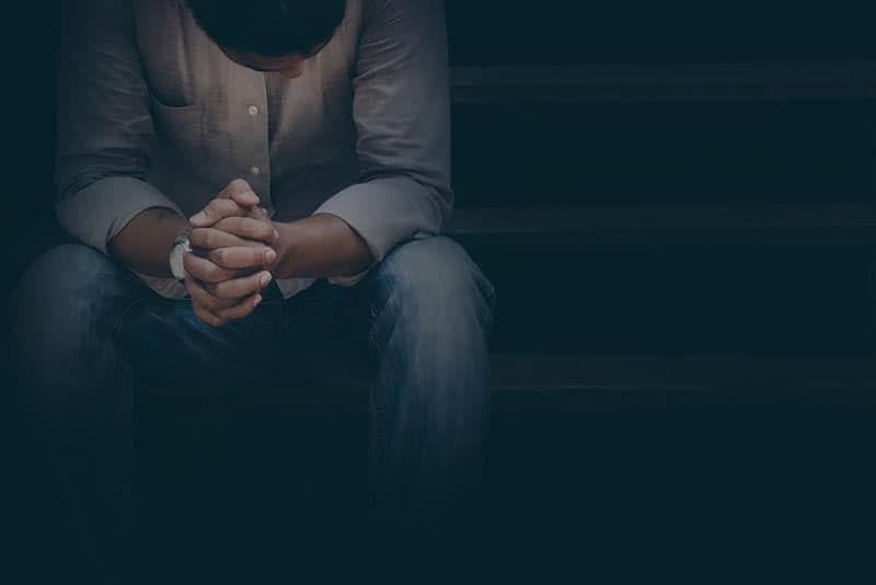 حزين ، رجل مكتئب يرتدي قميصًا أبيض يجلس في الظلام