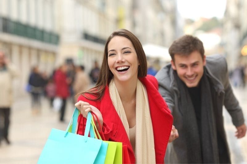 المرأة، جر الرجل، عن، التسوق، بينما، حمل أكياس التسوق