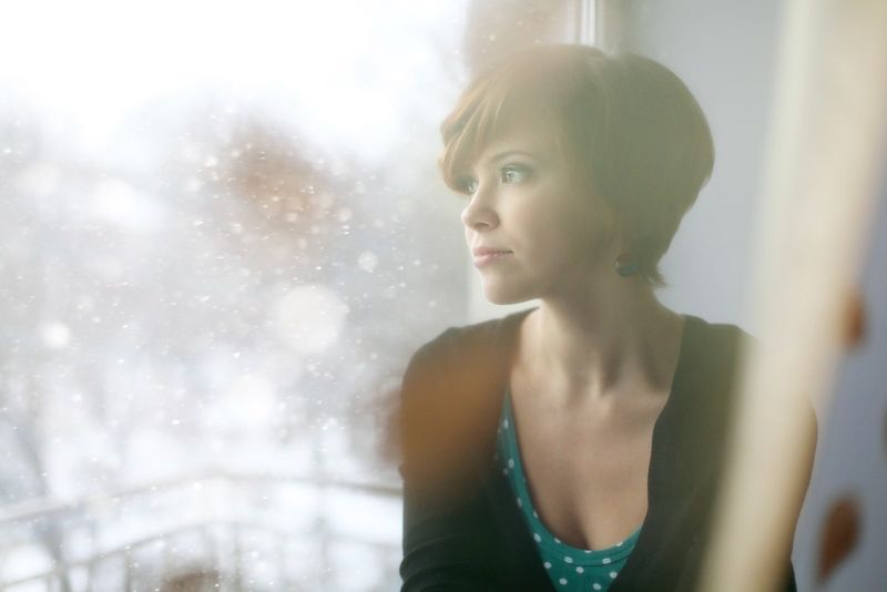 eine kurzhaarige brünette sitzt am fenster und denkt nach