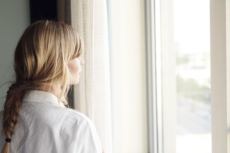 blonde Frau, die durch das Fenster schaut