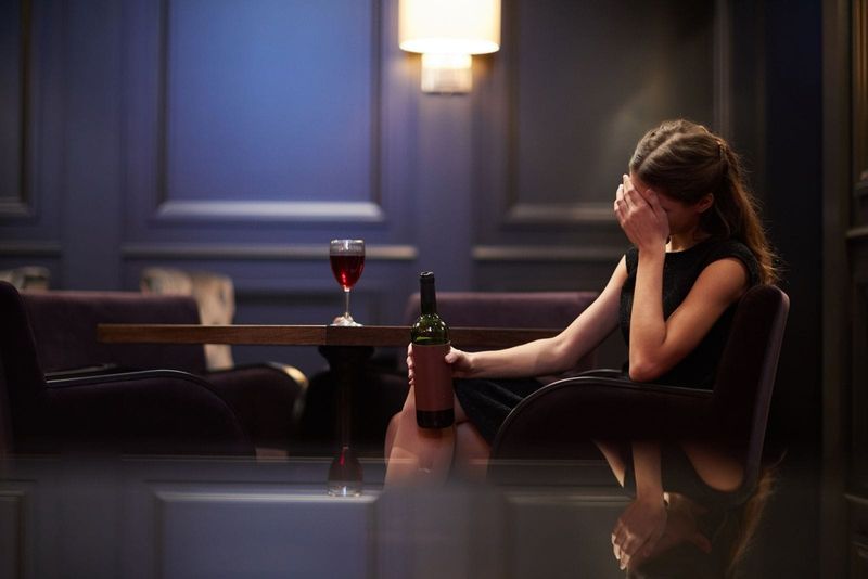 jeune femme solitaire triste avec une bouteille de vin rouge dans un hôtel de luxe