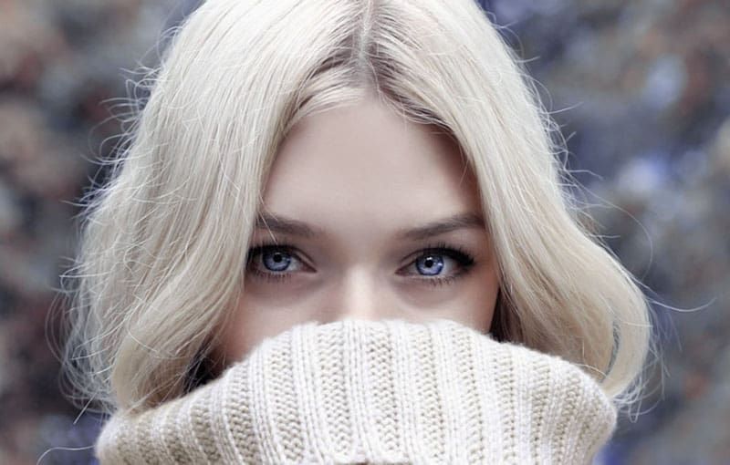 schöne blonde frau, die ihren mund mit ihrem pullover in der fokusfotografie bedeckt