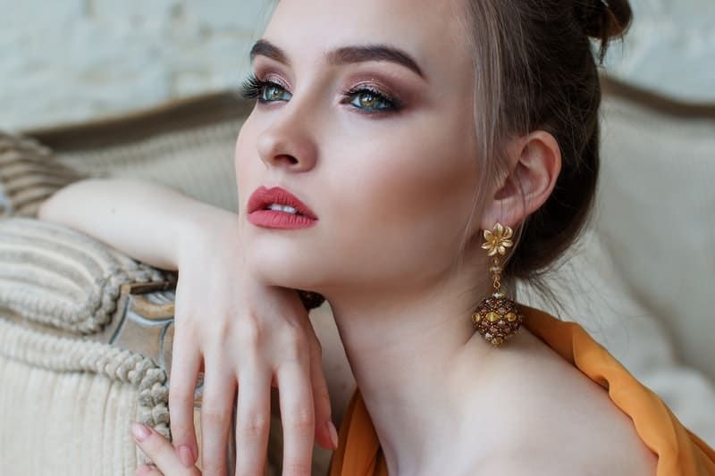 Frau in Make-up, die formell gekleidet ist, sieht in die Ferne