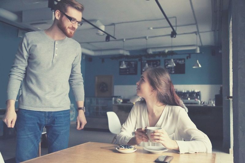 người đàn ông đến gần người phụ nữ uống cà phê bên trong quán cà phê
