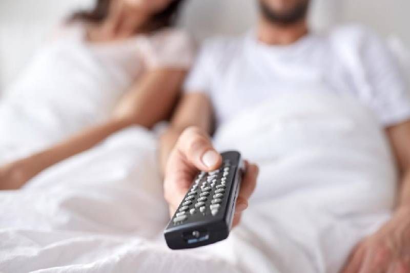 comandament a distància que porta un home assegut al costat d