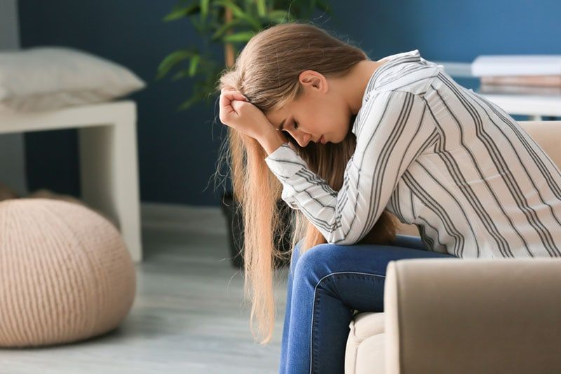 dona trista asseguda al sofà preocupada