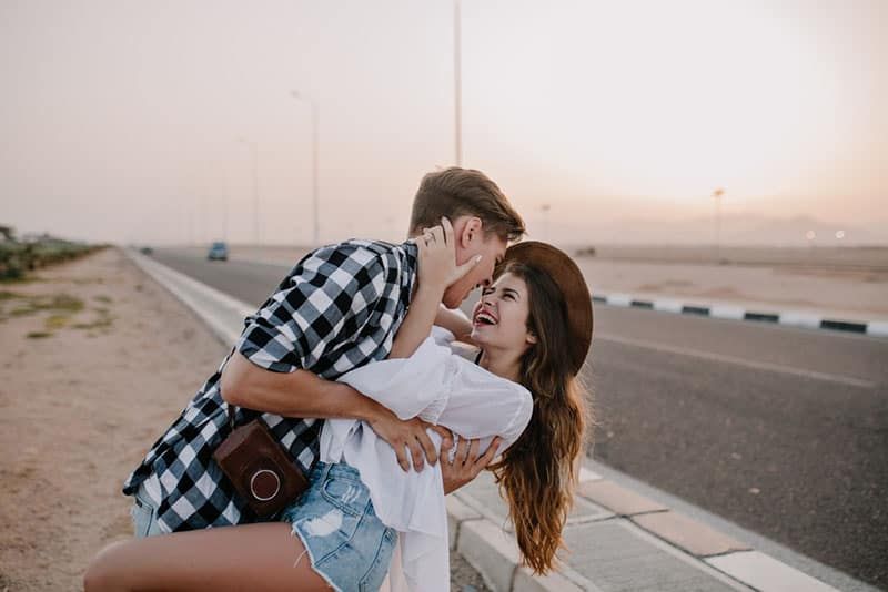 người đàn ông ôm người phụ nữ mỉm cười trên đường