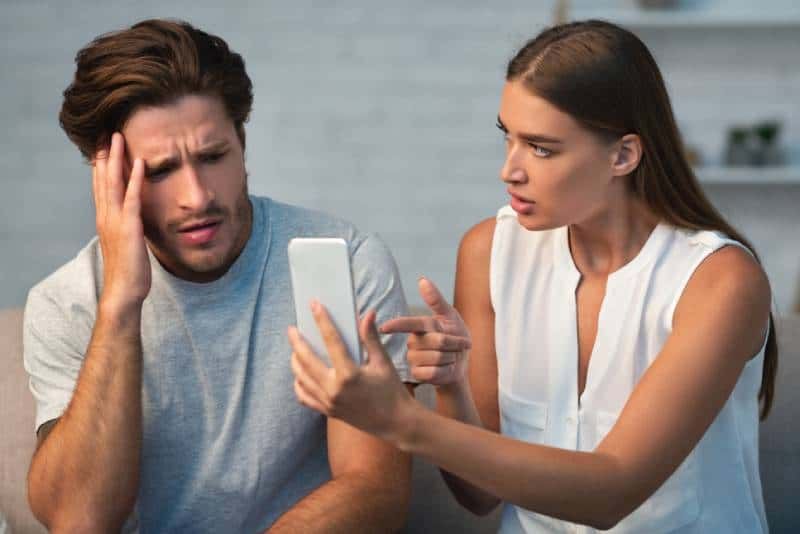 dziewczyna pokazuje swojemu zdradzającemu chłopakowi jego telefon komórkowy