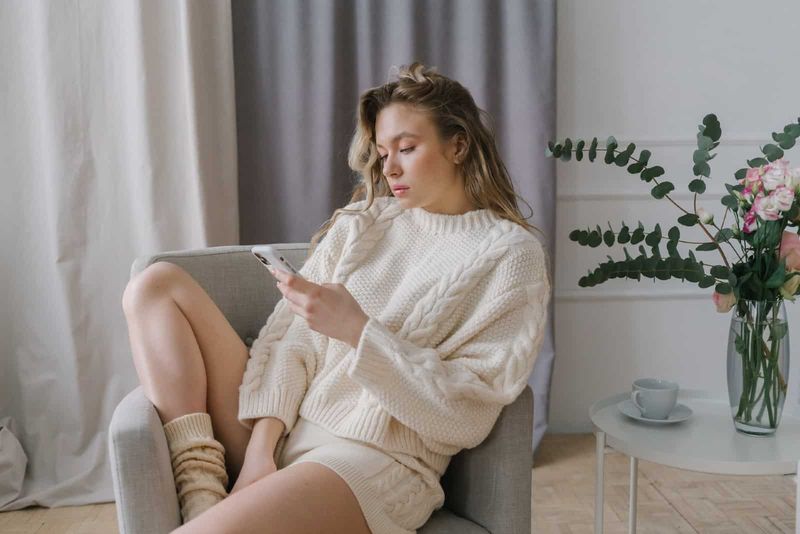 γυναίκα που χρησιμοποιεί smartphone ενώ κάθεται σε γκρι πολυθρόνα