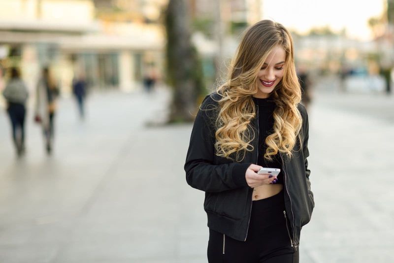 blond bølget hår kvinde, der smiler og sender sms