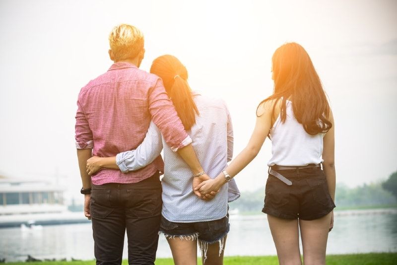 男人抱着女人的同时抱着另一个女人