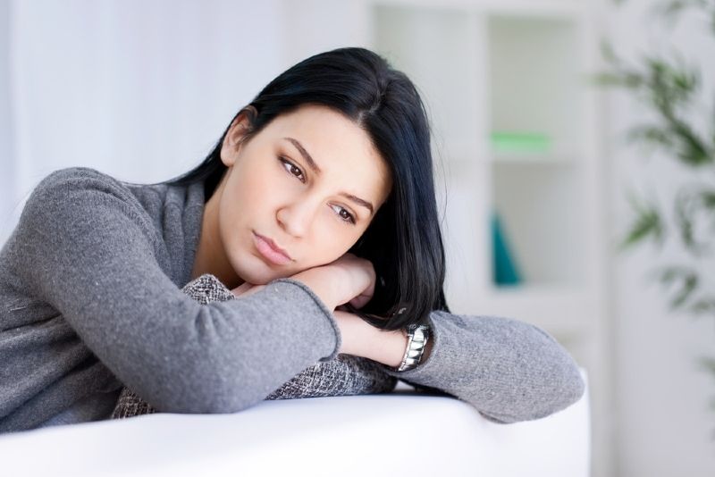 灰色毛衣靠在沙发上的悲伤女人