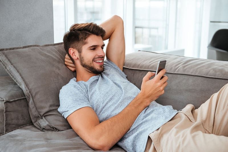 uśmiechnięty mężczyzna patrzący na telefon