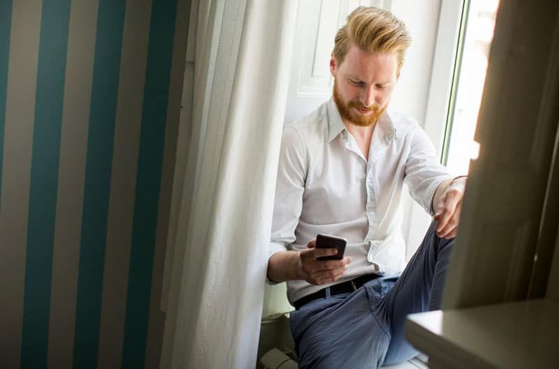 mężczyzna odbierający telefon w pokoju w pobliżu niebiesko-białej tapety