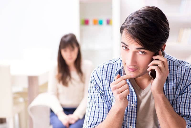 mężczyzna potajemnie odbiera telefon od kobiety za nim