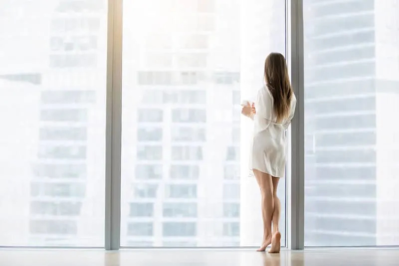   Junge Frau im Abendkleid blickt durch das Bodenfenster