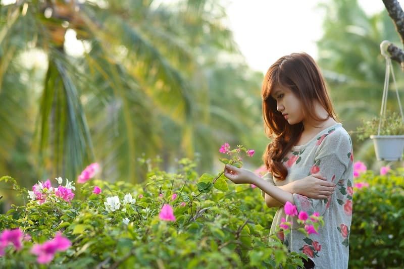 wanita memegang bunga di taman