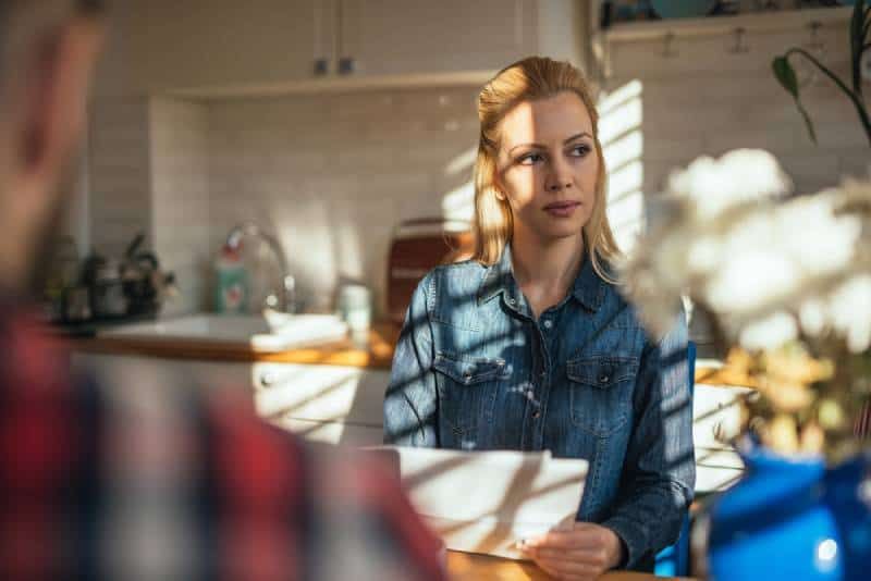 wanita duduk di dapur dan berpikir