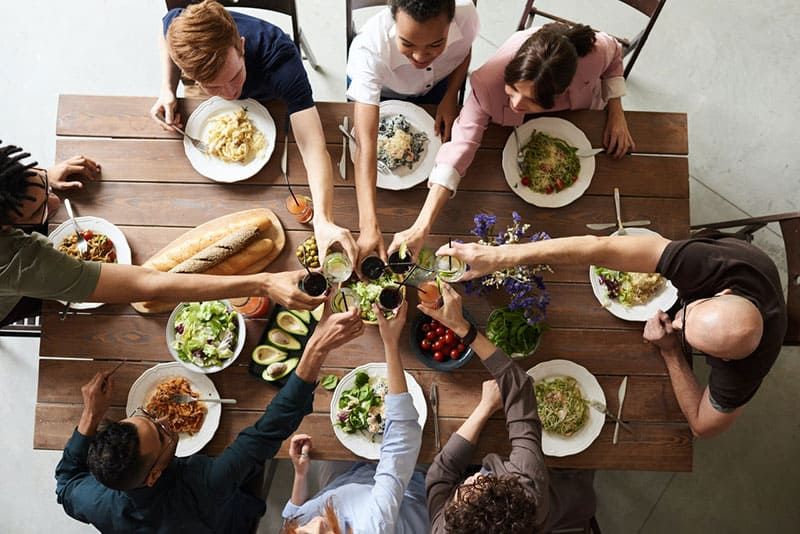 Gruppe von Menschen, die Toast über dem Esstisch machen