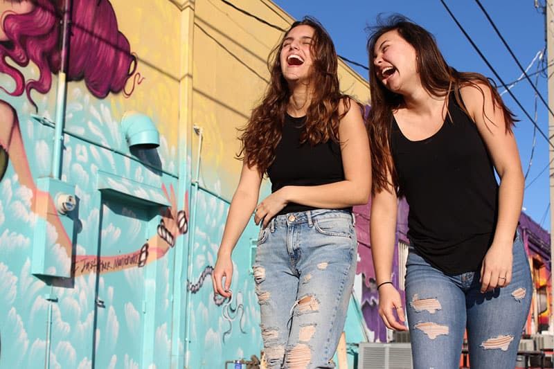 Twee dames lachen terwijl ze over straat lopen