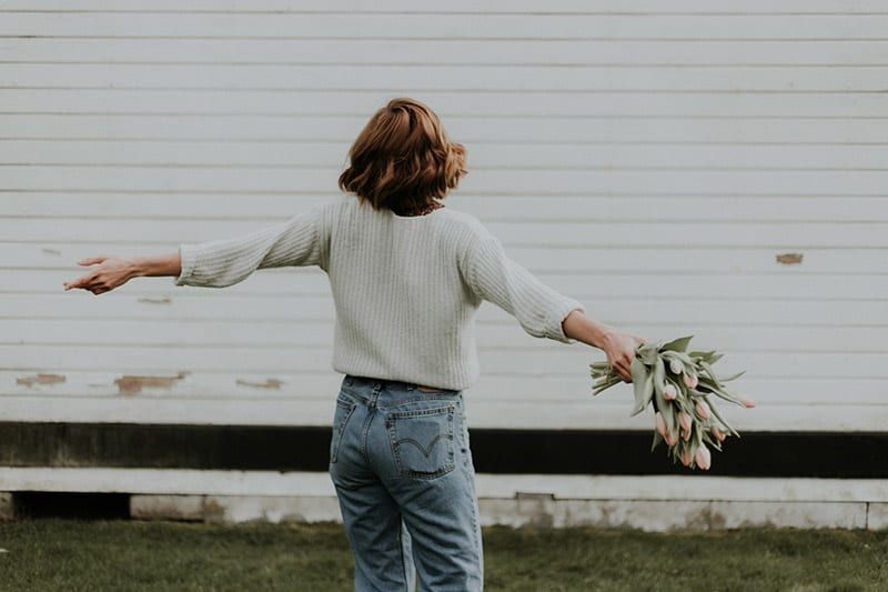 Achterkant van vrouw met gespreide armen met boeket tulpen