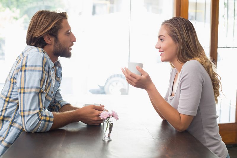 um homem e uma mulher sentados à mesa tomando café e conversando