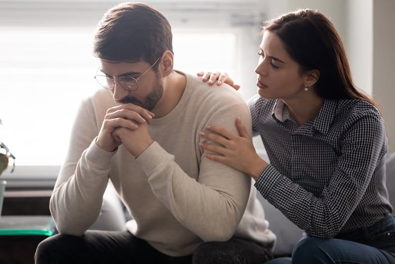 người phụ nữ an ủi một người đàn ông và chạm vào vai anh ta