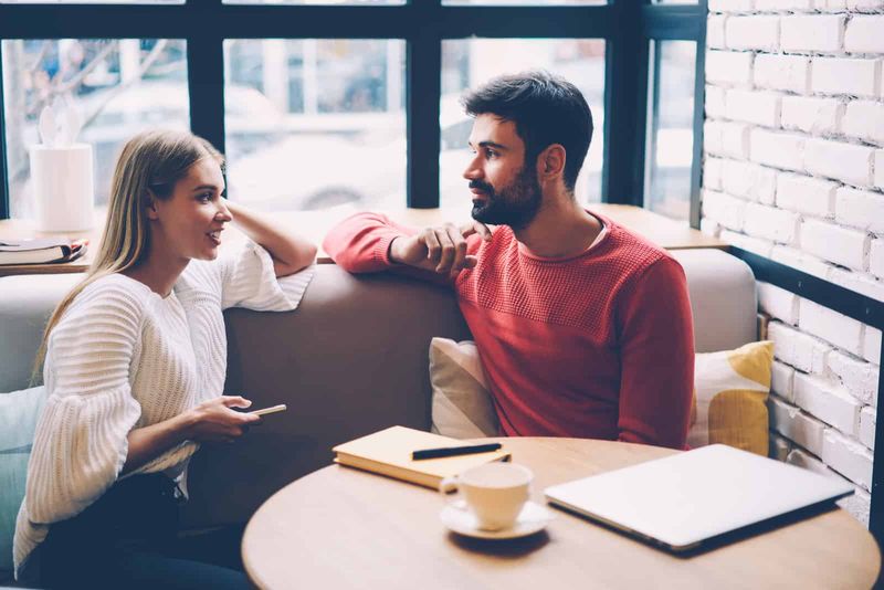 een man en een vrouw zitten op de bank en praten
