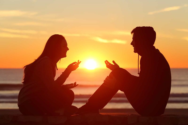 uśmiechnięty mężczyzna i kobieta siedzą na ścianie i rozmawiają