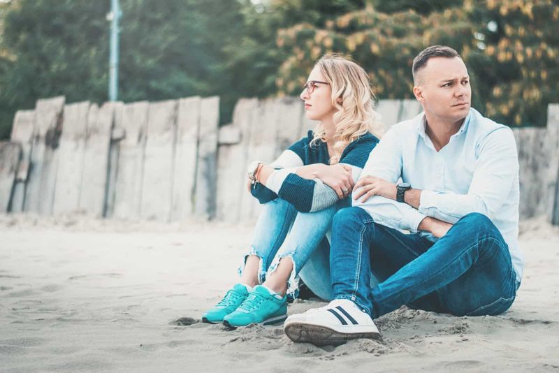 mężczyzna odwrócił się plecami do kobiety, gdy siedzieli na plaży