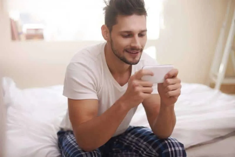   home assegut escrivint al seu telèfon al matí