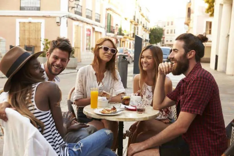   amics que es diverteixen asseguts a una cafeteria del carrer