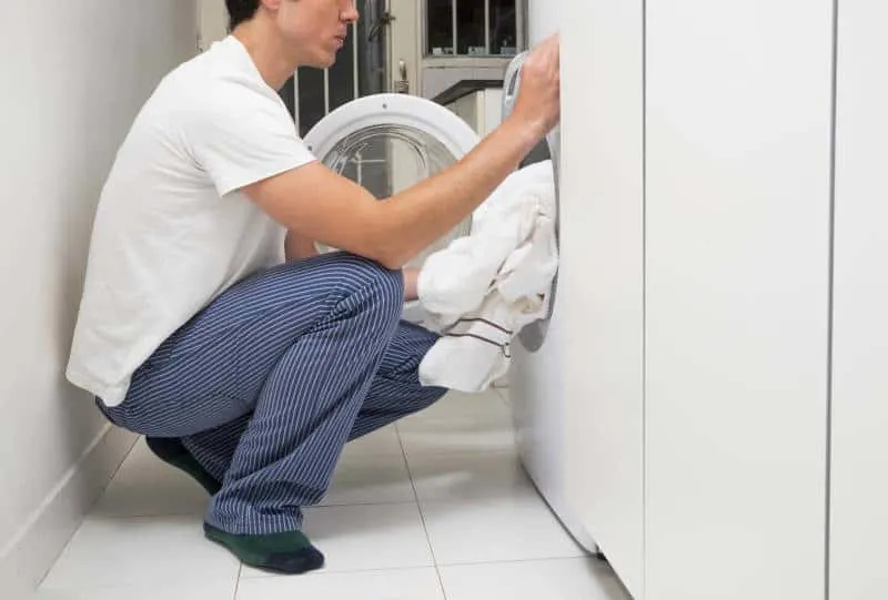   home de primer pla posant la roba a la rentadora