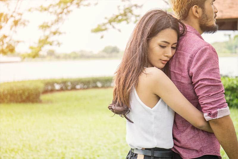 người đàn ông hôn lên cổ bạn gái đang mỉm cười