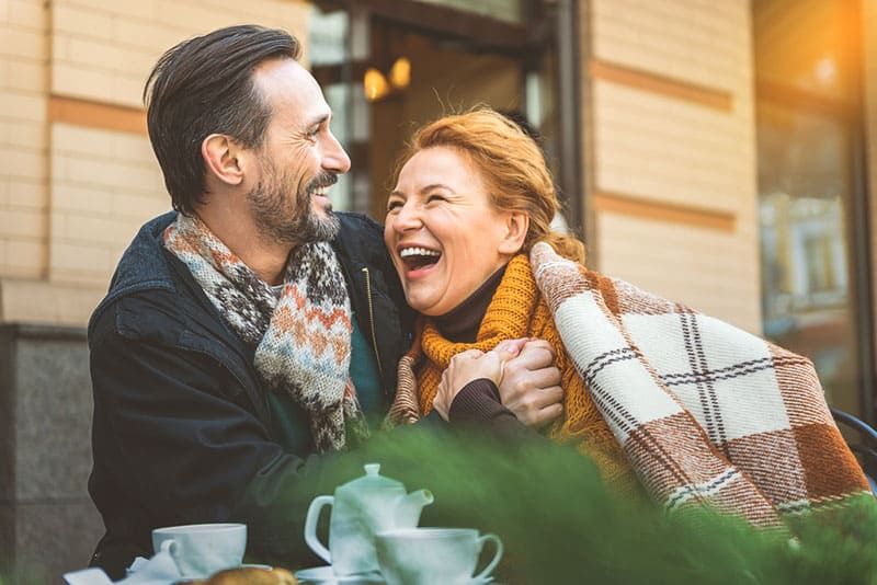 casal feliz rindo no café