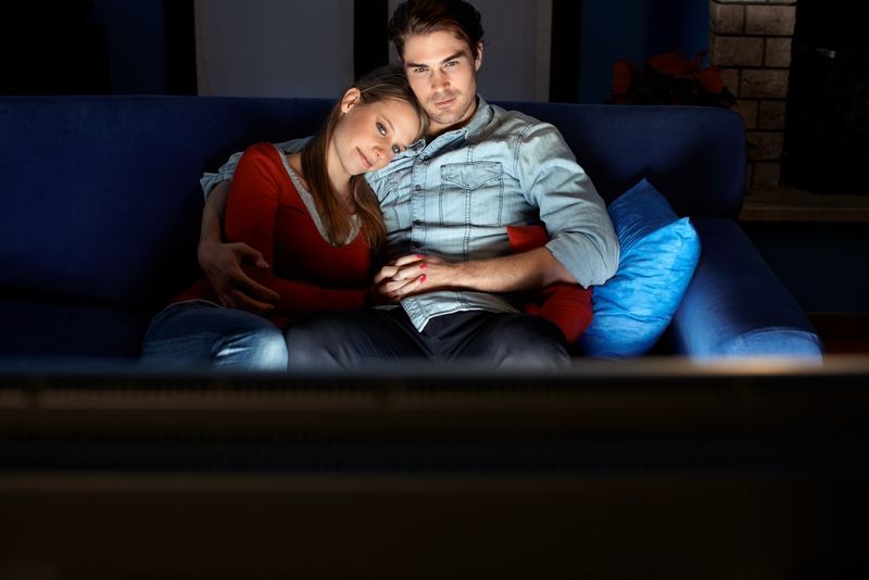 pria dan wanita menonton film sambil duduk di sofa